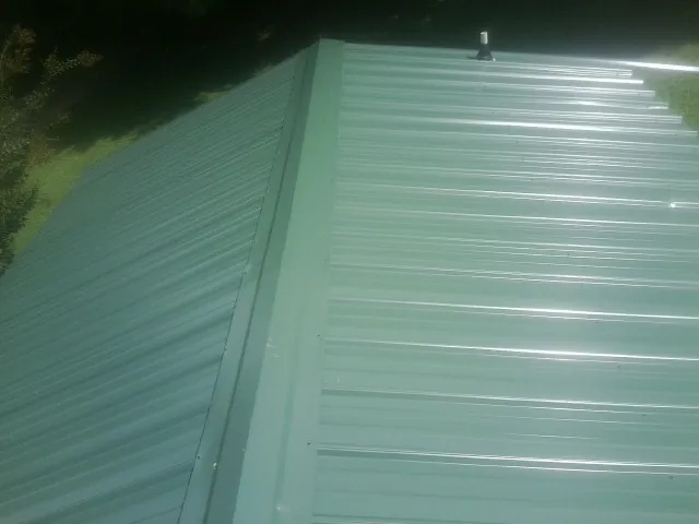 New green metal panels meeting at the ridge of a roof — Flat Roof Repair work by our crew in Grapeview