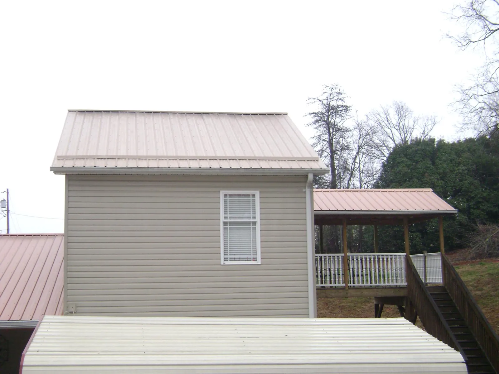 Tan metal roofs on a two story addition and attached porch, from a Roof Replacement job in Grapeview