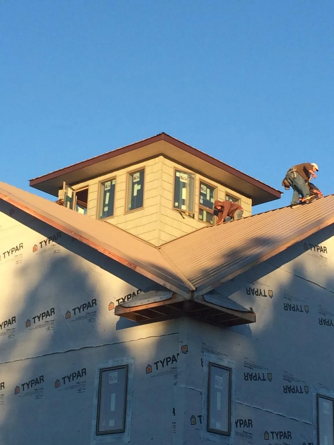 Roofers working around a rooftop cupola on a new metal roof at sunset — Roof Waterproofing in Grapeview by Roofing Brothers